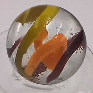 May include: A clear glass marble with colorful swirls. The marble features orange, yellow, and brown stripes that twist and turn within the transparent sphere. A classic toy with a vintage aesthetic.