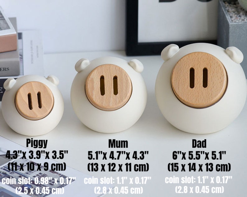 May include: Three white ceramic piggy banks with wooden coin slots. The piggy banks are labeled "Piggy", "Mum", and "Dad" with their dimensions in inches and centimeters.