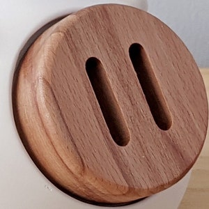 May include: A close-up of a wooden knob with two oval-shaped cutouts. The knob is a light brown color and has a smooth, polished finish.