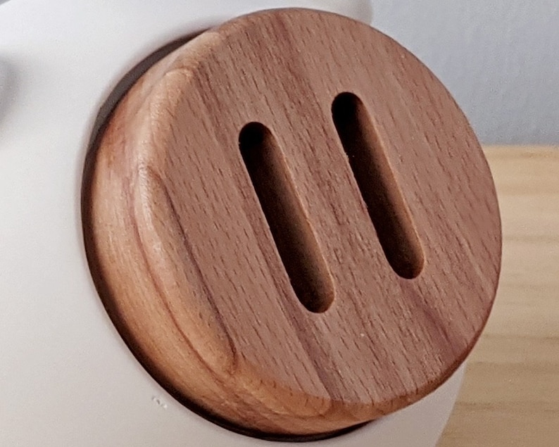 May include: A close-up of a wooden knob with two oval-shaped cutouts. The knob is a light brown color and has a smooth, polished finish.