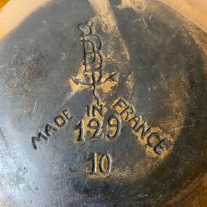 K&ouml;nnte beinhalten: Nahaufnahme des Bodens einer braunen Keramikschale mit schwarzer Glasur. Die Schale ist mit "Made in France 129 10" gekennzeichnet.