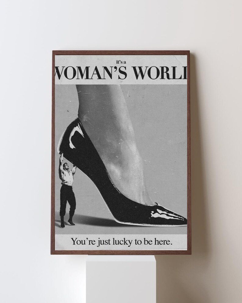 May include: Black and white framed print with the text "it's a WOMAN'S WORLD" and "You're just lucky to be here." The image features a high-heeled shoe and a small figure.