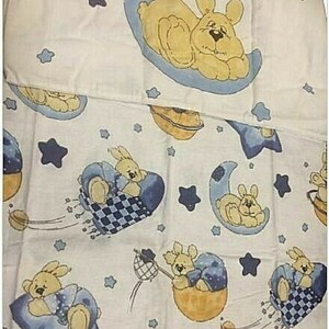 May include: White baby bedding featuring a repeating pattern of yellow bunnies on blue moons, stars, and other celestial elements. The bunnies are shown sleeping on moons and riding in baskets.