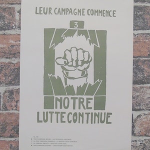 Puede incluir: Póster vintage con texto y gráficos verdes sobre fondo blanco. El texto dice "LEUR CAMPAGNE COMMENCE" y "NOTRE LUTTE CONTINUE". Un puño cerrado está centrado. El póster se muestra contra una pared de ladrillos.