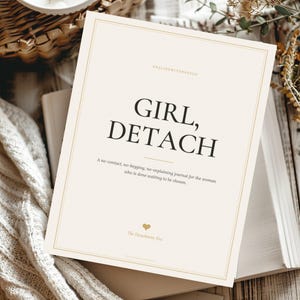 May include: A rectangular journal with a cream-colored cover featuring a thin gold border. The text reads: GIRL, DETACH. A no-contact, no-begging, no-explaining journal for the woman who is done waiting to be chosen. Includes a small gold heart icon.