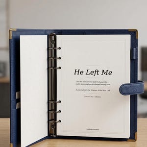 Peut inclure: Un journal bleu marine avec des coins dorés et une fermeture à bouton-pression. Le journal est ouvert sur une page avec le texte "He Left Me" et le sous-titre "A Journal for the Woman Who Was Left". Le journal fait partie de la collection "I Chose to Stay".