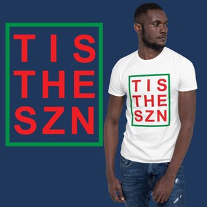 Op de afbeelding: Wit T-shirt met een groene en rode box met de tekst "TIS THE SZN" in rode letters.