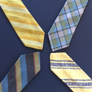 Puede incluir: Cuatro corbatas de diferentes patrones en una variedad de colores, incluyendo amarillo, azul y verde. Las corbatas están dispuestas en forma de cruz sobre un fondo azul oscuro.