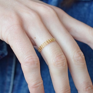 Peut inclure: Une bague en chaîne dorée sur un doigt avec un vernis à ongles bordeaux.