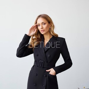 Peut inclure: Robe blazer noire &agrave; double boutonnage, ceinture et poches. La robe a des manches longues et un col crant&eacute;. Le mot "SETIQUE" est imprim&eacute; sur la robe.