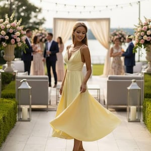 May include: A woman in a flowing, pale yellow dress with spaghetti straps twirls outdoors. The dress falls to mid-calf length. She wears beige heels. The background includes a garden party setting with floral arrangements and guests.