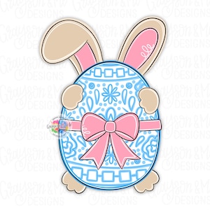 Peut inclure: Un œuf de Pâques bleu et blanc avec un nœud rose et des oreilles de lapin. L'œuf a un motif décoratif et est entouré des oreilles de lapin.