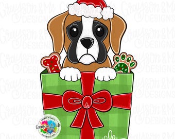 May include: A digital illustration of a Boxer dog wearing a Santa hat, peeking out of a green gift box with a red bow. The box contains gingerbread cookies shaped like a bone and a paw print. The image has the text "Grayson & Me Designs".