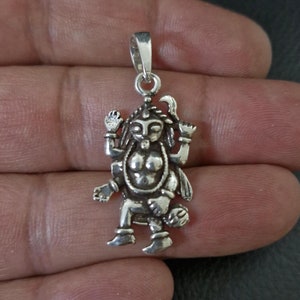 Può includere: Ciondolo in argento con una rappresentazione dettagliata di una divinità indù con più braccia e un'espressione feroce.