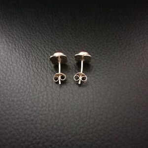 K&ouml;nnte beinhalten: Ein Paar silberne Ohrstecker mit roten Edelsteinen. Die Ohrringe haben ein schlichtes Design und sind perfekt f&uuml;r den Alltag.