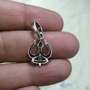 May include: Silver pendant featuring a trident design. The pendant is detailed with black enamel and has a loop for attaching to a chain.