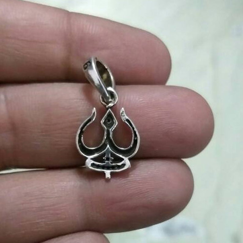 May include: Silver pendant featuring a trident design. The pendant is detailed with black enamel and has a loop for attaching to a chain.