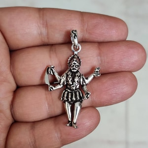 Può includere: Ciondolo in argento con una rappresentazione dettagliata di una dea indù con più braccia, che tiene vari oggetti. Il ciondolo è finemente lavorato e ha uno stile tradizionale.