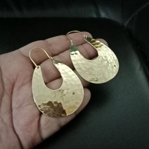 Peut inclure: Une paire de boucles d'oreilles créoles ovales en or martelé. Les boucles d'oreilles sont grandes et ont une texture martelée.