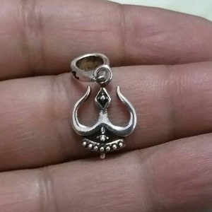 May include: Silver pendant featuring a three-pronged design with black accents. The pendant has a loop at the top for attaching to a chain.