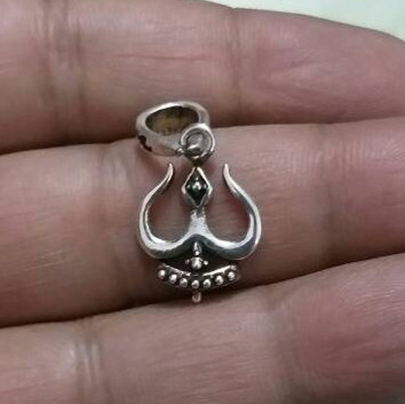 May include: Silver pendant featuring a three-pronged design with black accents. The pendant has a loop at the top for attaching to a chain.