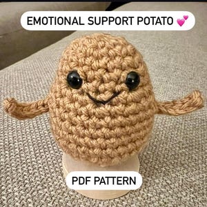 May include: Crocheted brown potato with a smiling face and arms outstretched. The potato is labelled "Emotional Support Potato" and "PDF Pattern".