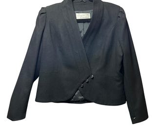 May include: A black blazer with a unique wrap-style front and three decorative buttons. The jacket features a notched collar and padded shoulders. The blazer is hanging on a black hanger.