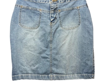 May include: Light blue denim skirt with two front pockets and a button closure. The skirt is hanging on a black hanger. The skirt has a classic, casual style.