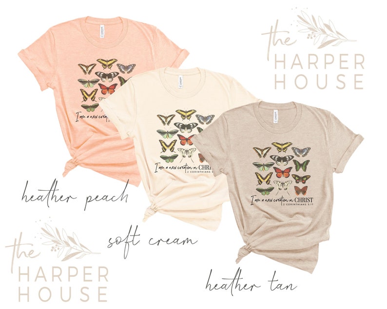 Puede incluir: Tres camisetas en diferentes colores: melocot&oacute;n, crema suave y marr&oacute;n. Cada camiseta presenta un dise&ntilde;o de mariposas coloridas y el texto "Soy una nueva creaci&oacute;n en CRISTO 2 Corintios 5:17".