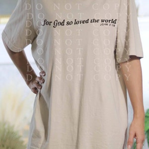 May include: A beige t-shirt with the text "for God so loved the world" and the scripture reference "John 3:16" printed on the front.