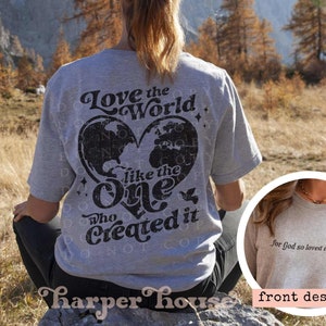 May include: A grey t-shirt with a black graphic on the back that says "Love the World like the One Who Created it" with a world map inside a heart. The front of the shirt has the text "for God so loved the world" in black.