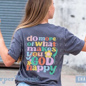 May include: A charcoal gray t-shirt with the text "do more of what makes you GOD happy" in colorful retro lettering with a flower graphic.