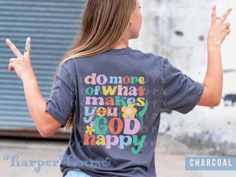 May include: A charcoal gray t-shirt with the text "do more of what makes you GOD happy" in colorful retro lettering with a flower graphic.