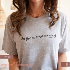 May include: Grey t-shirt with the text "For God so loved the world" and the Bible verse "John 3:16" printed on the front.