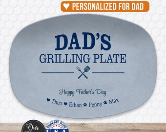 May include: An oval light blue serving plate featuring dark blue text that reads DAD'S GRILLING PLATE, Happy Father's Day, and the names Theo, Ethan, Penny, and Max. The design includes a small graphic of a fork and spatula crossed together.