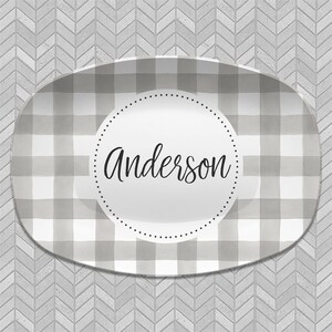 May include: A gray and white checkered oval serving platter with a white circle in the center. The circle has a black dotted border and the name "Anderson" written in black cursive.