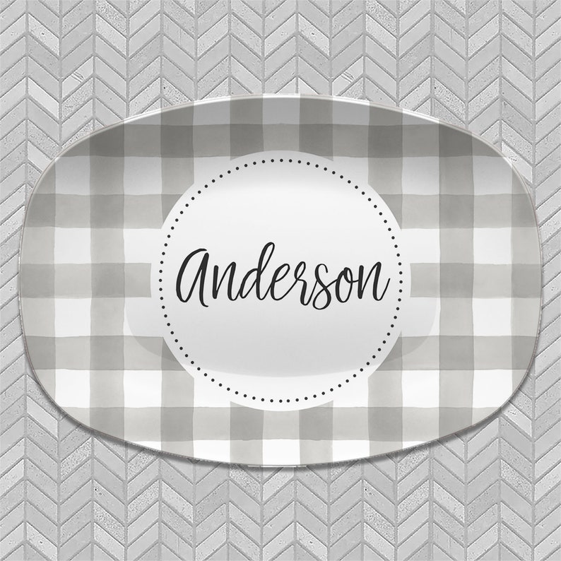 May include: A gray and white checkered oval serving platter with a white circle in the center. The circle has a black dotted border and the name "Anderson" written in black cursive.