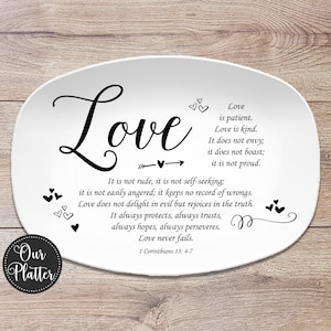 May include: White oval platter with the word "Love" in elegant script, accompanied by a passage from 1 Corinthians 13:4-7. The design includes decorative hearts and an arrow. The platter is a decorative item.