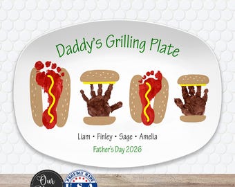 May include: Oval white platter with the text "Daddy's Grilling Plate" in green. The platter features handprint and footprint designs resembling hot dogs and hamburgers. Includes names and "Father's Day 2026".