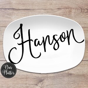 May include: White oval platter with the name "Hanson" in black script. The platter has a rounded edge and a logo that says "Our Platter" in a circle on the bottom left.