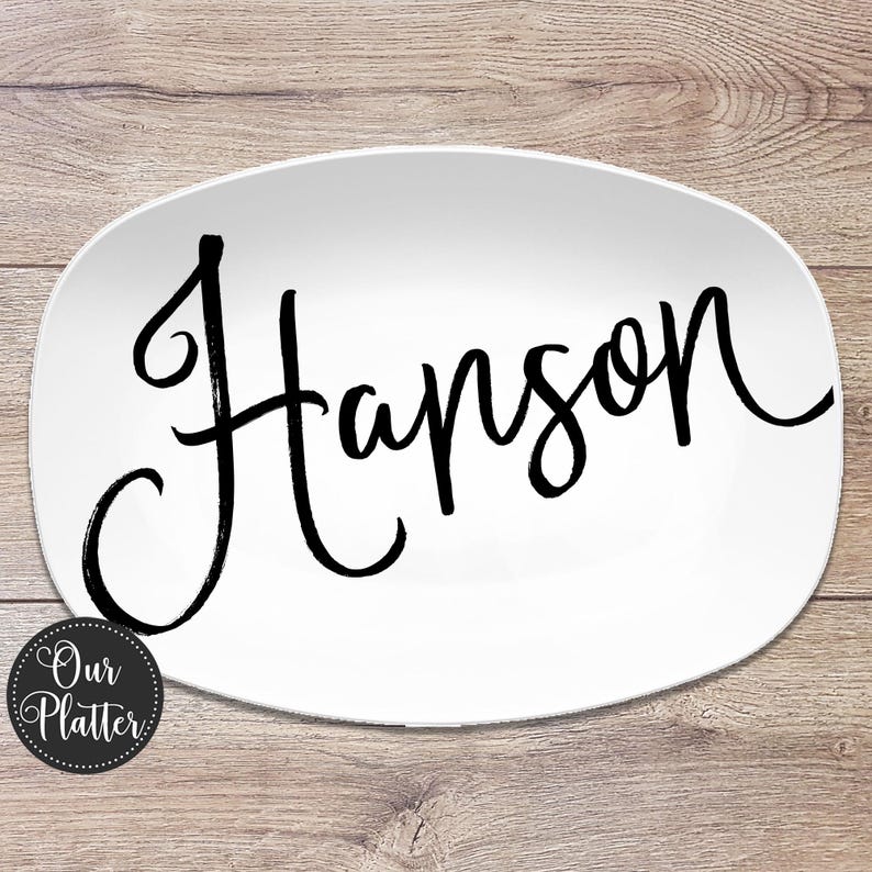 May include: White oval platter with the name "Hanson" in black script. The platter has a rounded edge and a logo that says "Our Platter" in a circle on the bottom left.