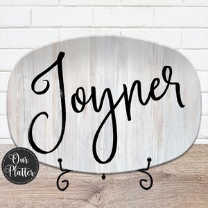 May include: Oval decorative platter featuring the word "Joyner" in black script. The platter has a white, wood-grain effect and is displayed on a black metal stand. The platter has the text "Our Platter" in a circular logo.