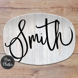May include: Oval serving platter with a white wood grain design. The word "Smith" is written in a black cursive font across the centre. The platter has a round logo that says "Our Platter".