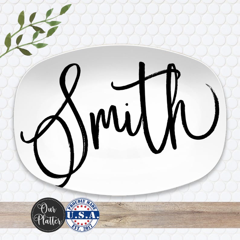 May include: White oval platter with the name "Smith" in large, black, cursive lettering. The platter has a simple, elegant design, suitable for serving food. Made in the U.S.A.