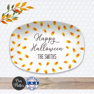 May include: White oval platter with a candy corn pattern and the words "Happy Halloween" and "THE SMITHS" in black script. The platter is decorated with yellow, orange, and white candy corn. A decorative fall branch is in the upper left corner.