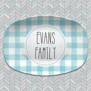 May include: A light blue and white checkered oval serving platter with a white circle in the center. The circle has black text that reads "Evans Family".