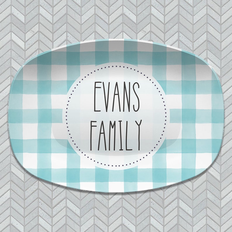 May include: A light blue and white checkered oval serving platter with a white circle in the center. The circle has black text that reads "Evans Family".