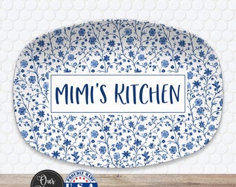 May include: Oval platter with a white background and a blue floral pattern. The words "MIMI'S KITCHEN" are in a white rectangle in the center. The platter has a "Proudly Made U.S.A." sticker.