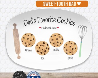May include: An oval white ceramic platter featuring the text "Dad's Favorite Cookies" and "Made with Love". The design includes a wooden rolling pin, a wire whisk, and four chocolate chip cookie illustrations labeled with the names Ariana, Jon, Willie, and Dixie.
