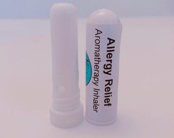 May include: A white plastic aromatherapy inhaler with a removable cap. The body of the inhaler features a label with the text Allergy Relief Aromatherapy Inhaler printed in black, alongside a partial blue circular logo on the side.